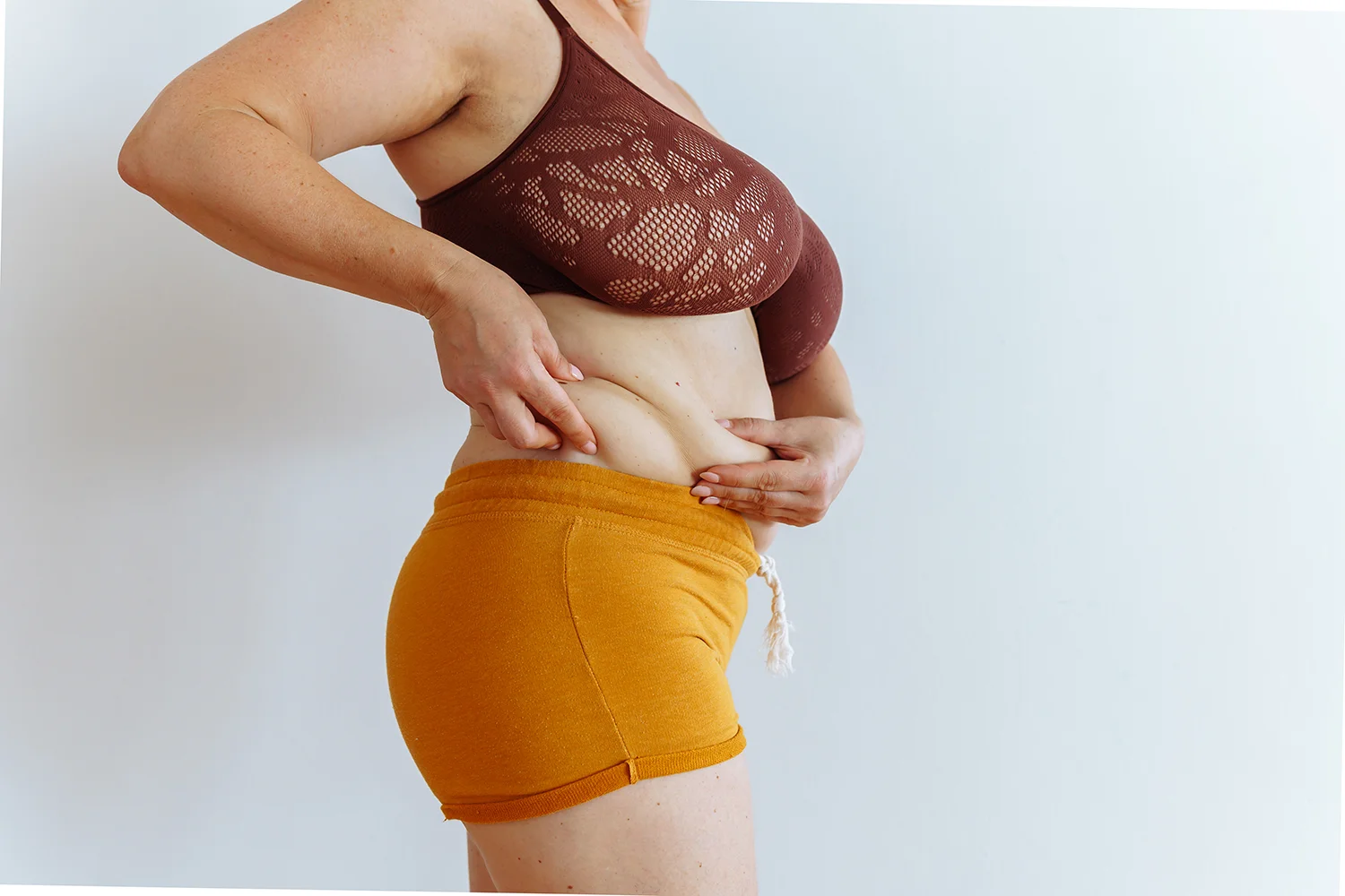 adult female examining her body shape at home