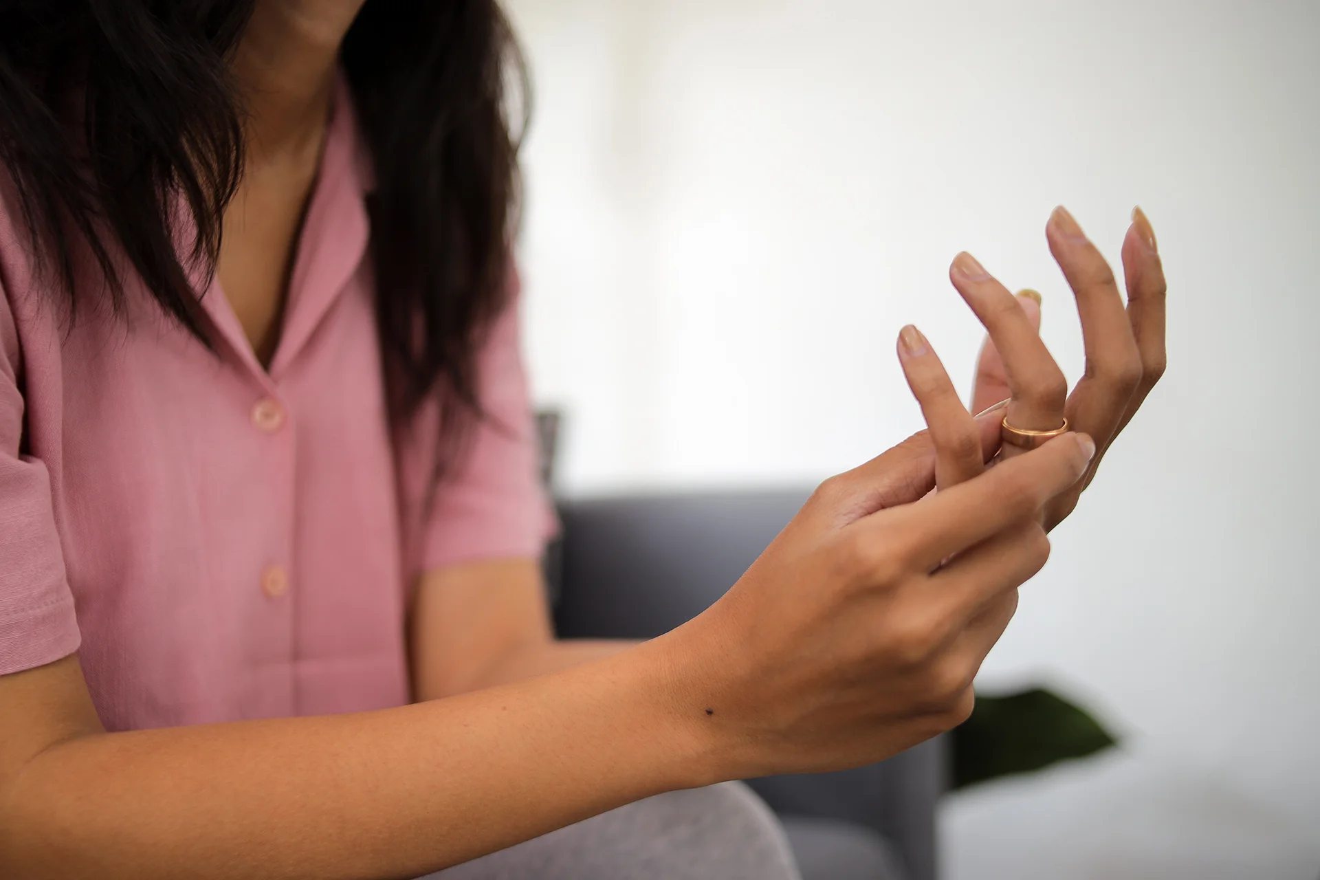 close up woman taking off wedding ring indoors