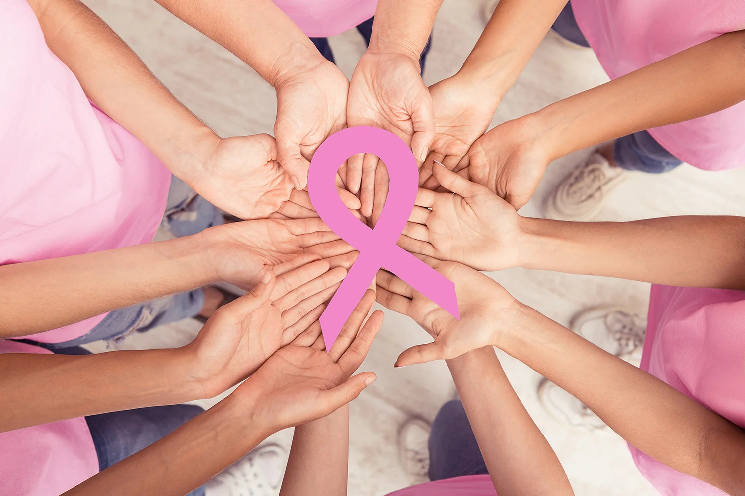 hands coming together for cause with pink ribbon