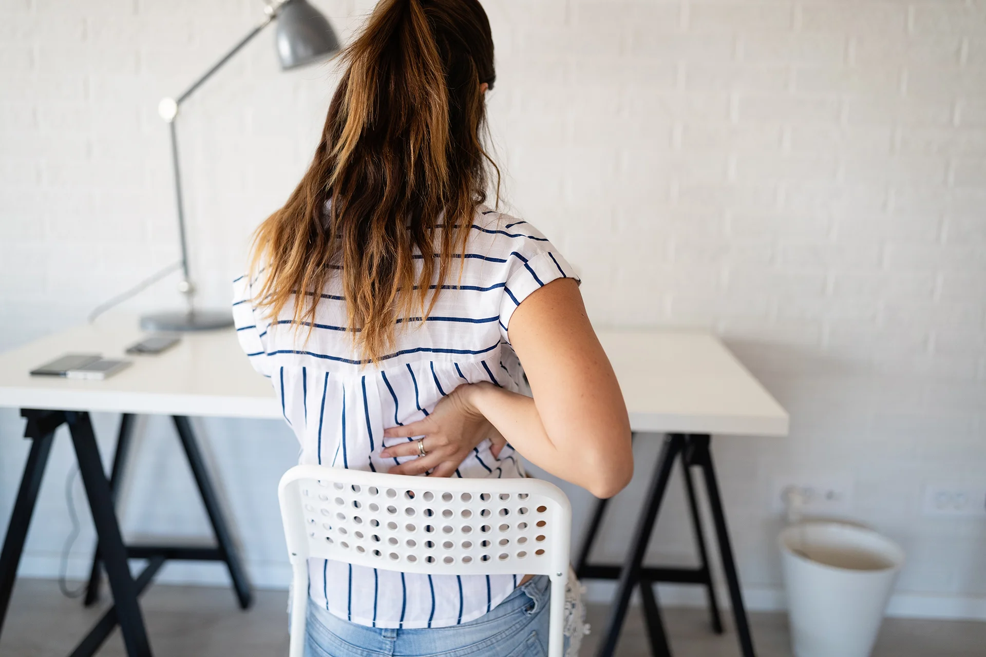 overworked woman with back pain in office with bad