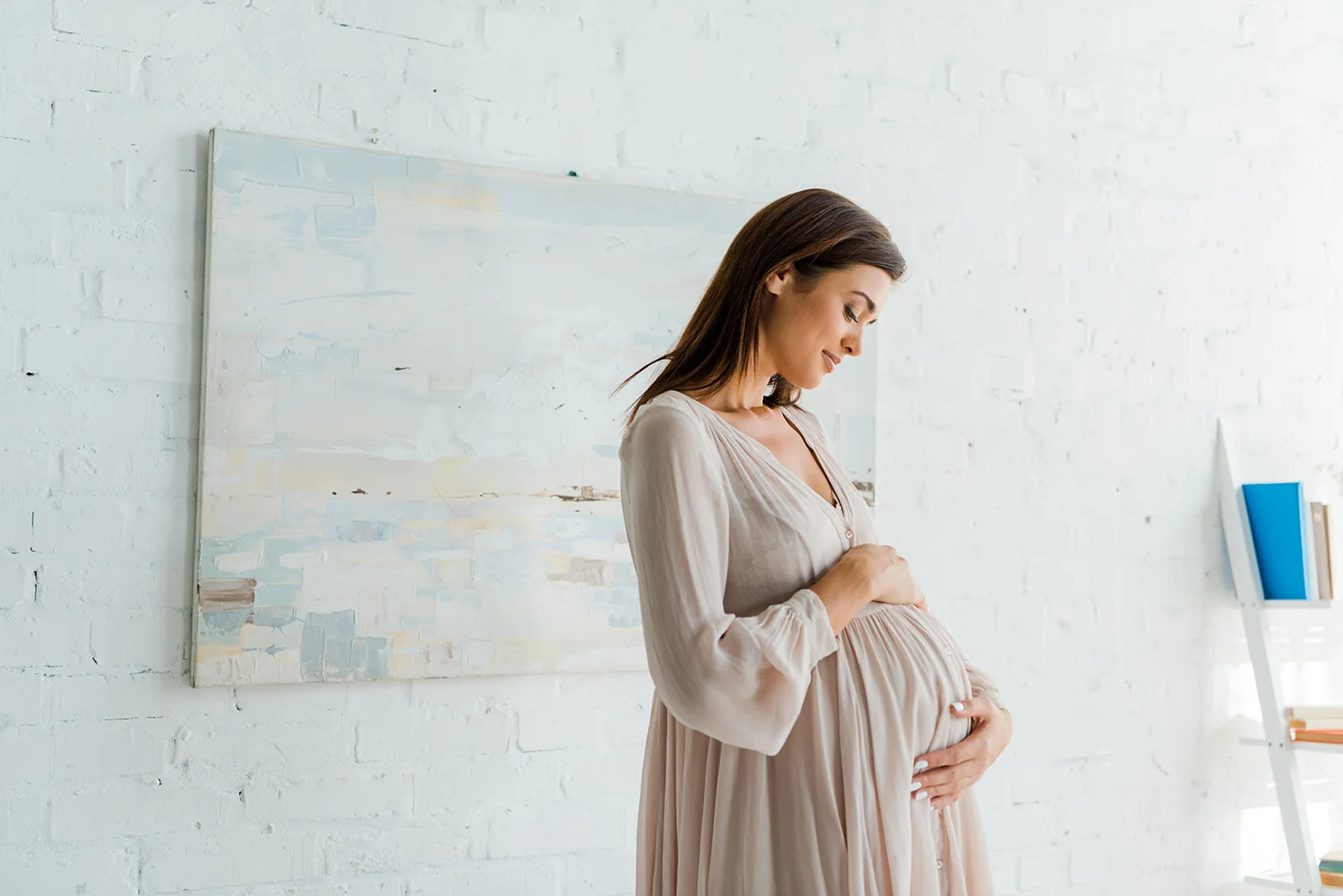 pregnant woman in dress embracing her belly