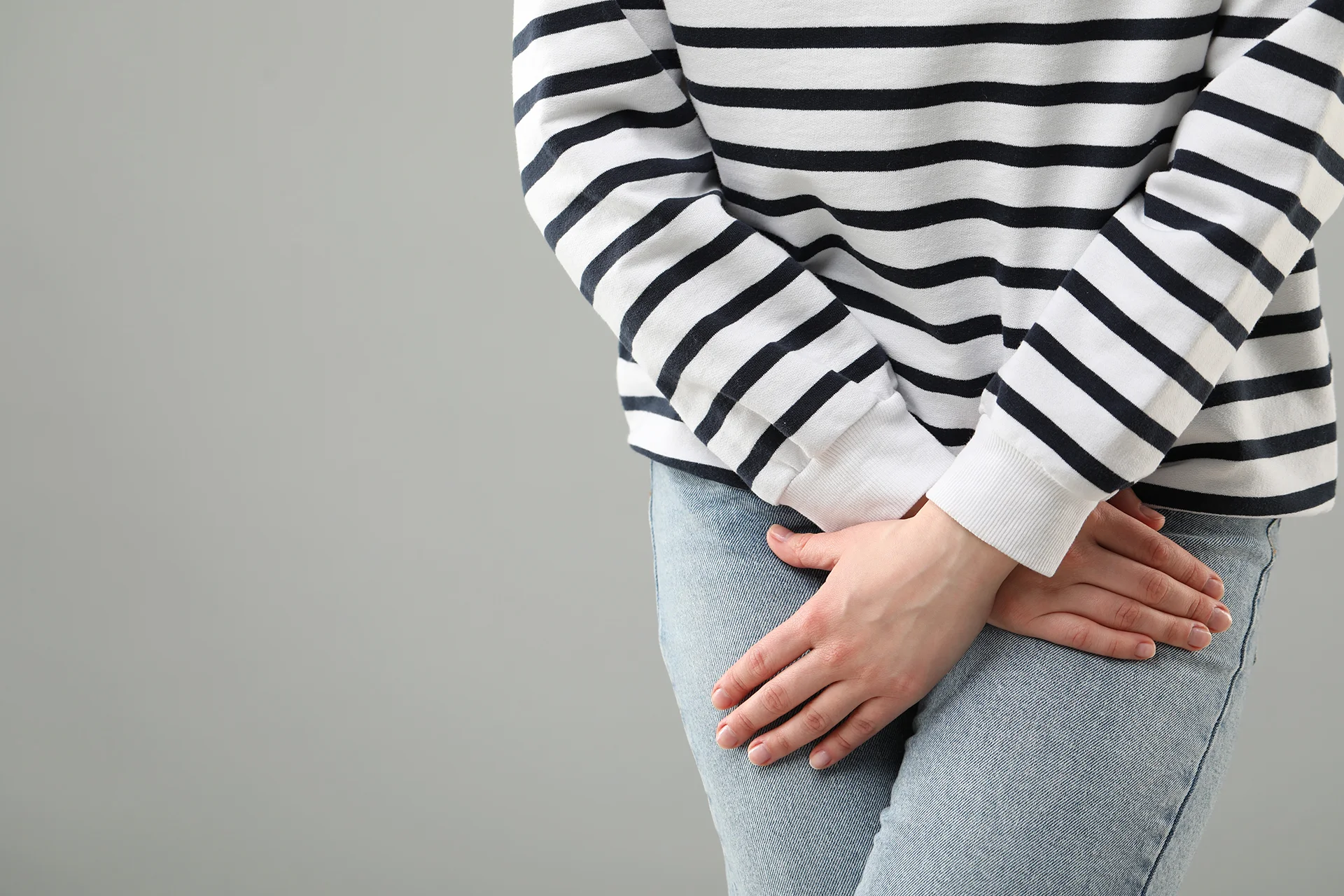 woman holds hands over lower abdomen area