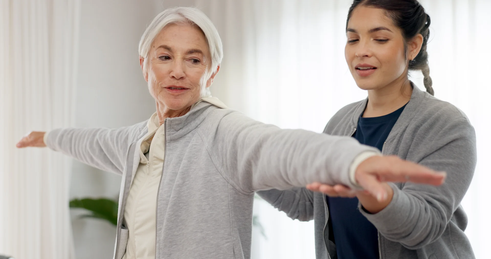 senior woman stretching with a trainer at home